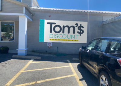 Tom's Discount exterior Non-lit dibound sign panel with 3M graphics mounted directly on building exterior.